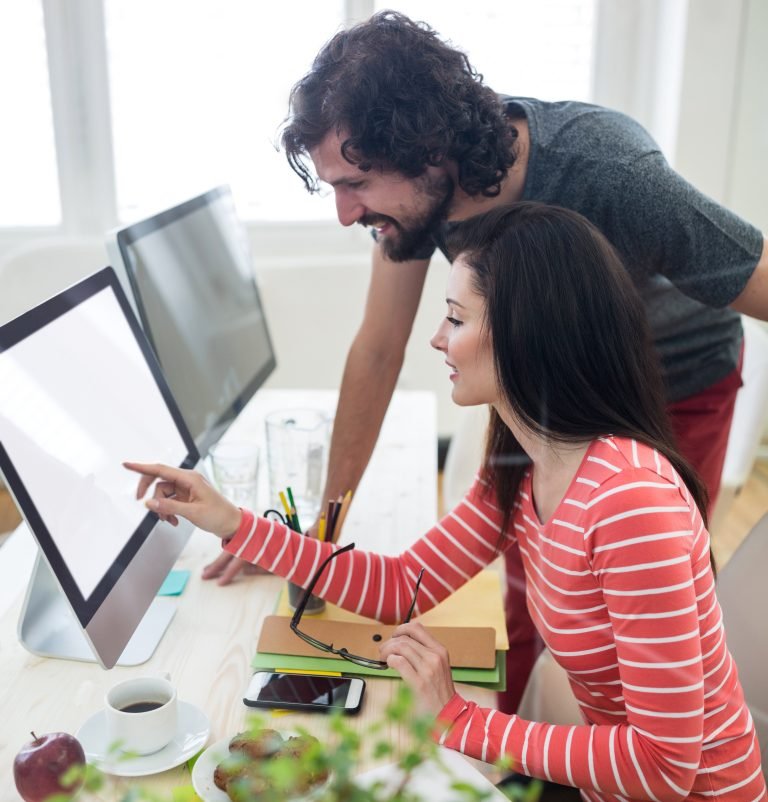 Male and female graphic designers interacting over computer
